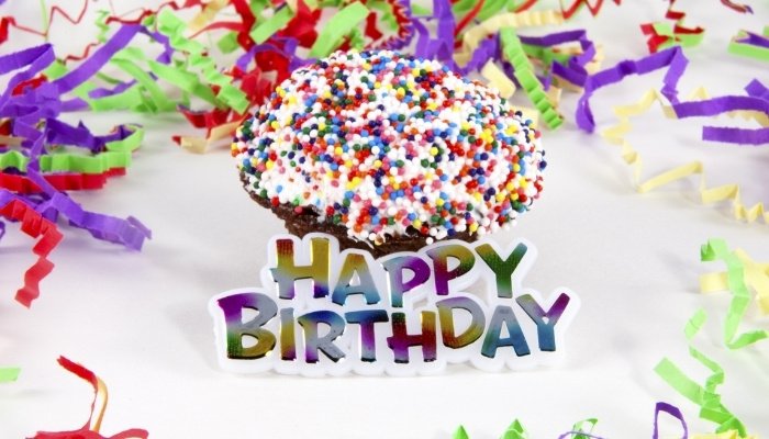 A birthday sign, cupcake, and colorful streamers.