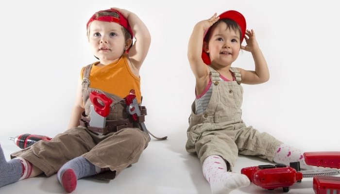 Two young boys dressed as construction workers with toy tools.
