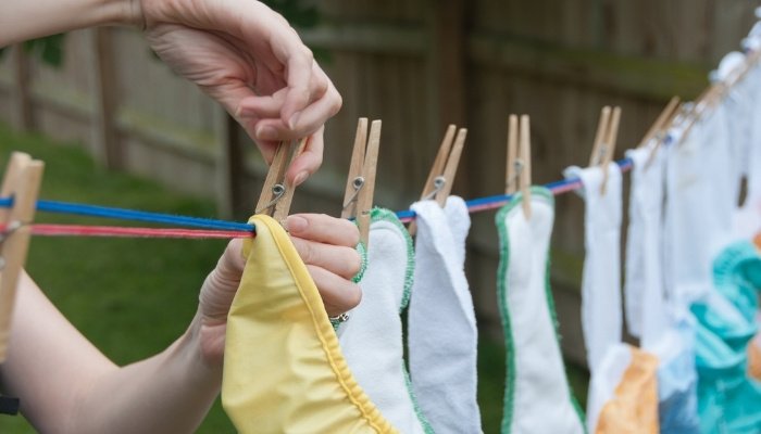 A woman hanging cloth diapers on a clothesline outside.
