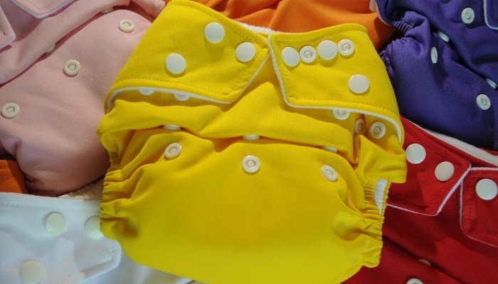 Brightly colored cloth diapers with a yellow one on top.