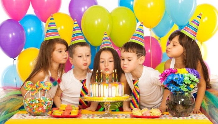 Four children gathered around birthday cake with yellow decorations.