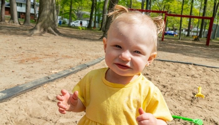 A little girl in a yellow dress at a playground.