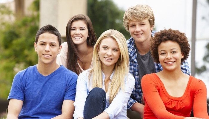 A group of five young teenagers sitting on outdoor steps.