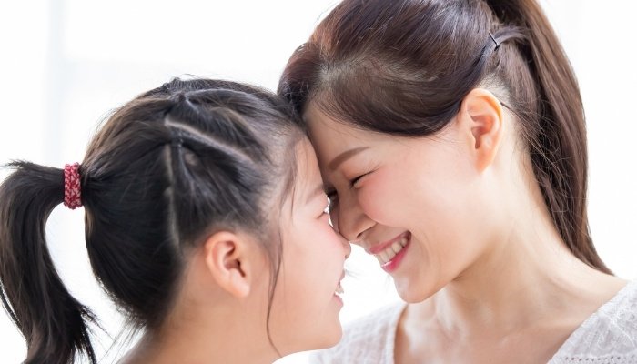 A mother and her young daughter smiling and rubbing noses.