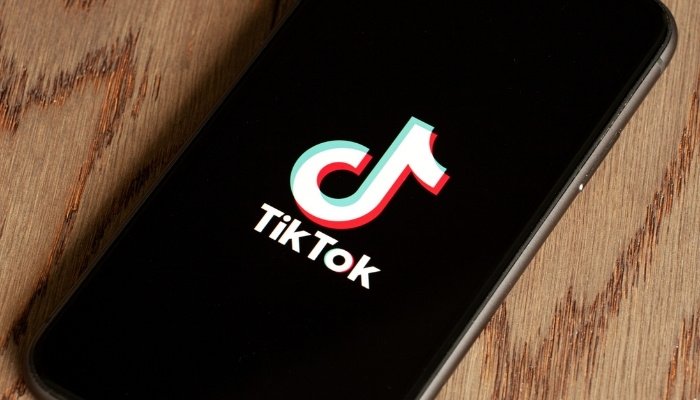 An iphone lying on a counter with the TikTok logo displayed.