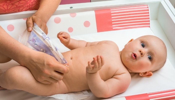 A cute baby with a surprised look on her face during a diaper change.