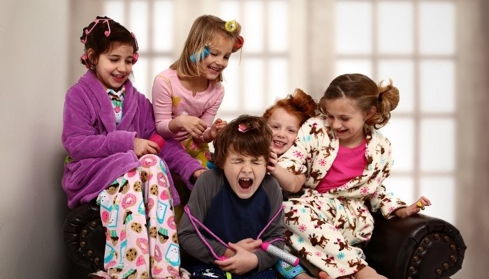 A group of girls at a slumber party torturing a little brother with hair styling.