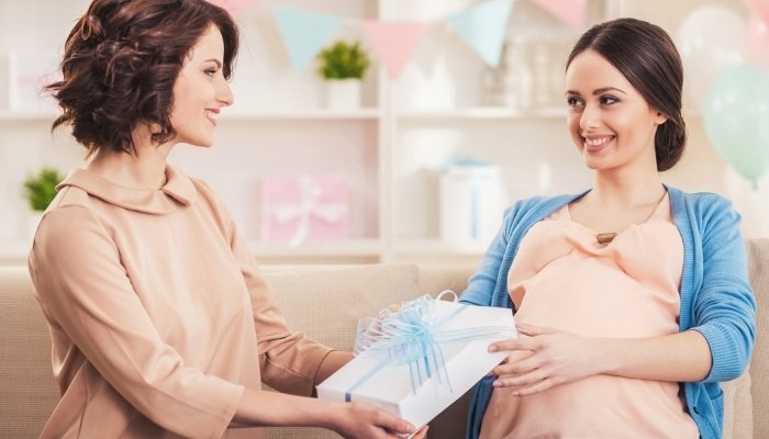 A lady giving her pregnant friend a present.