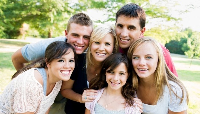 Mother, father, and four children posing for a family photo outside.