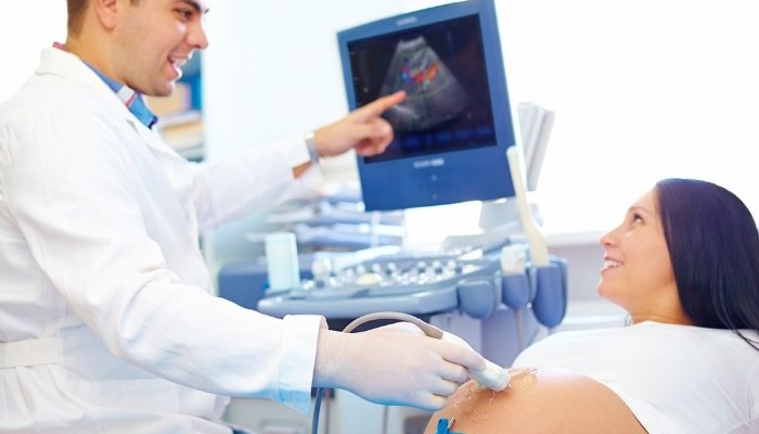 A pregnant woman having an ultrasound done at doctor's office.