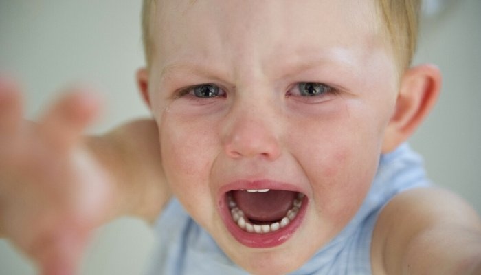A little boy is screaming and crying while asking to be held.