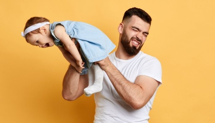 A cute baby girl laughing as she releases gas in her father's face.
