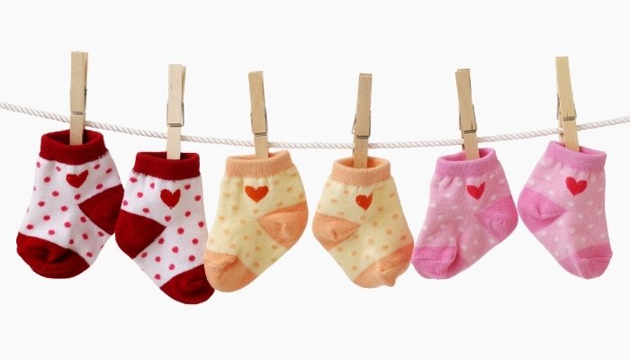 Three pairs of colorful baby socks hanging on a clothesline against a white background.