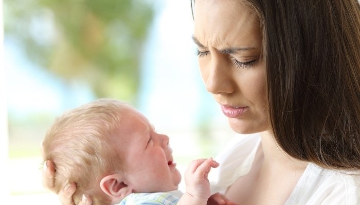 A worried mom looking down at her tired, cranky baby.