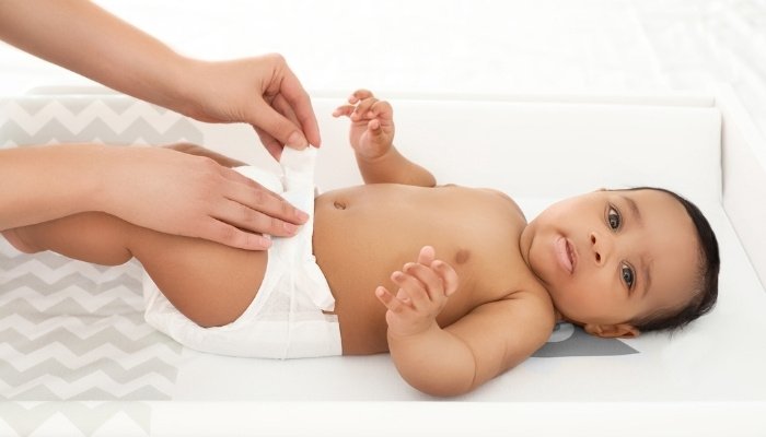A mother changing her baby's diaper on a changing table.