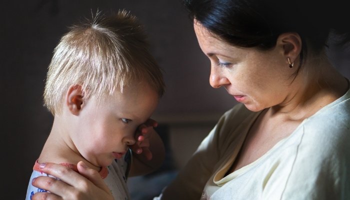 A young mother comforting her toddler who isn't feeling well.