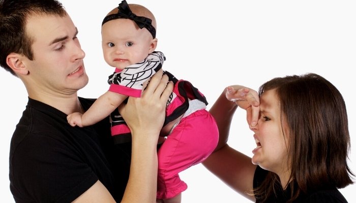 Parents holding their smelly baby girl in need of a diaper change.