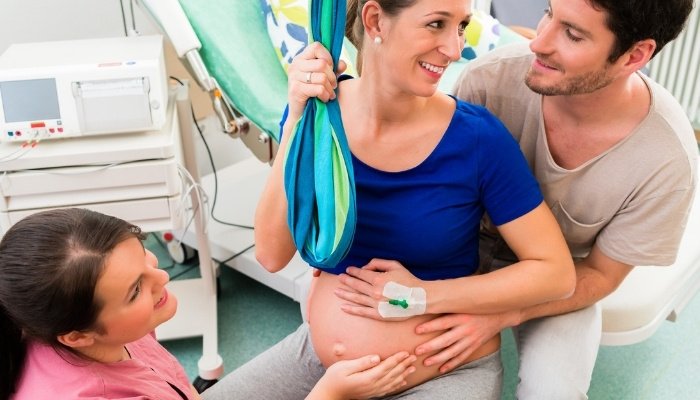 A pregnant lady, her husband, and a nurse preparing for active labor.