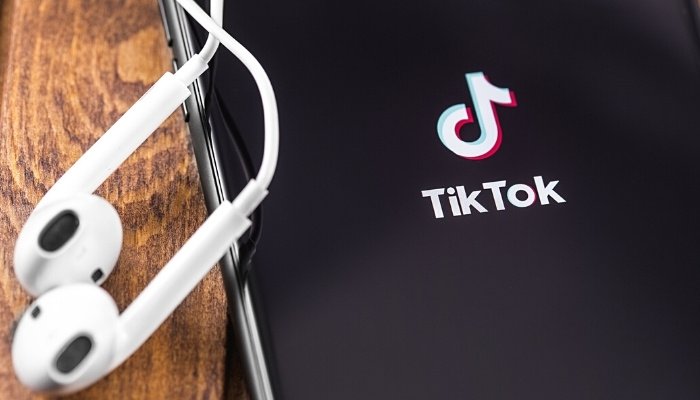 TikTok image on phone and white earbuds.