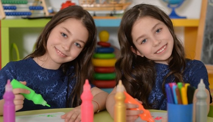 Two young twin sisters enjoying art class in school.