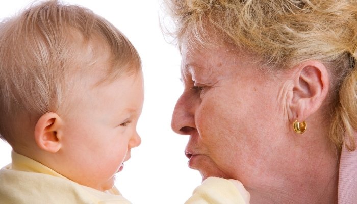 A grandma leaning in to give her grandchild a kiss on the nose.
