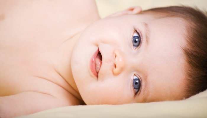 An adorable baby girl with blue eyes lying on her side.