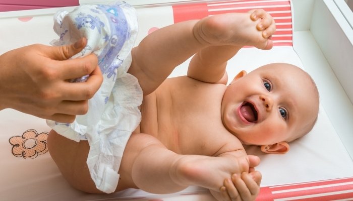 A mother in the middle of changing her cute baby's diaper.
