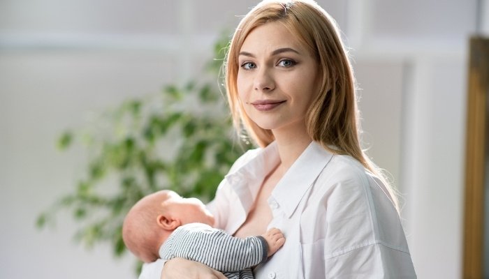 A young mother holding her breastfed son in her arms.