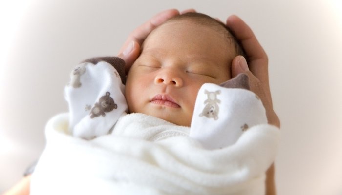A new baby being held in his father's hands.