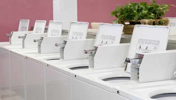 A row of empty washing machines at a public laundry facility.