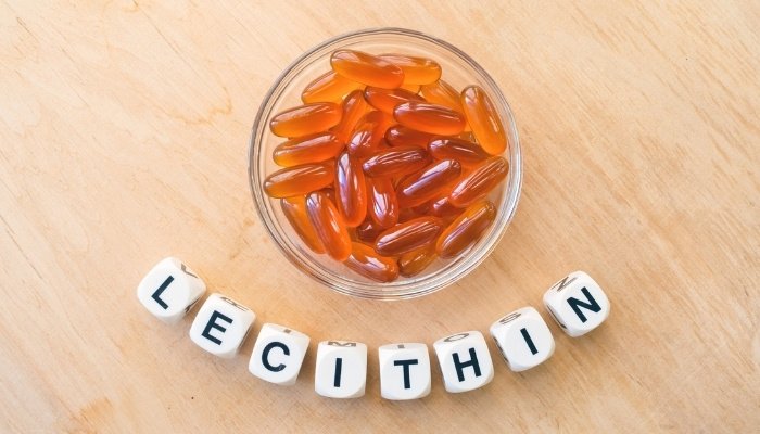 A bowl of softgels and white cubes arranged to spell LECITHIN.