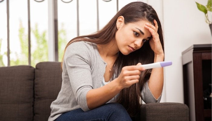 A young, worried girl staring at a home pregnancy test.