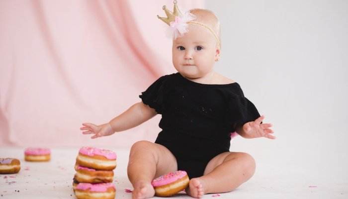 A baby girl celebrating her first birthday with a stack of donuts.