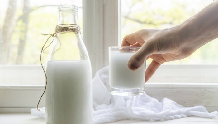 A glass jar of fresh, raw milk beside a freshly poured glass of milk.
