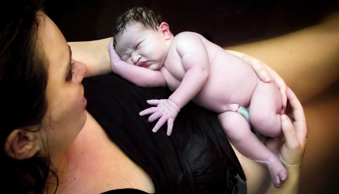 A mother holding her newborn baby after a water birth.