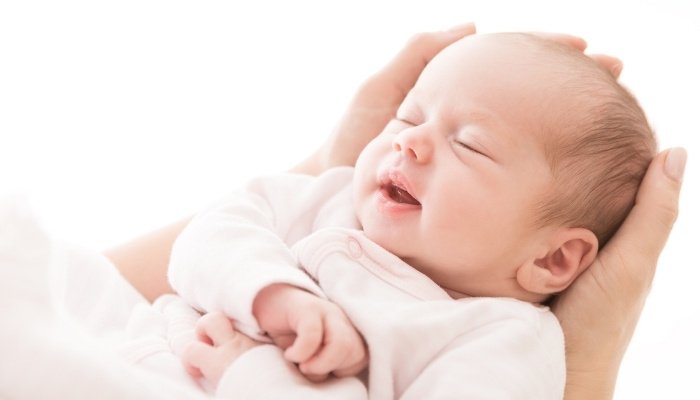 A brand-new baby being held in loving mother's hand.