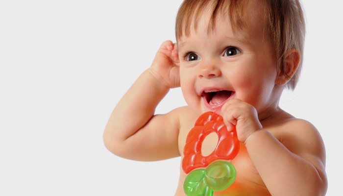 A baby boy playing with a strawberry-shaped teether.