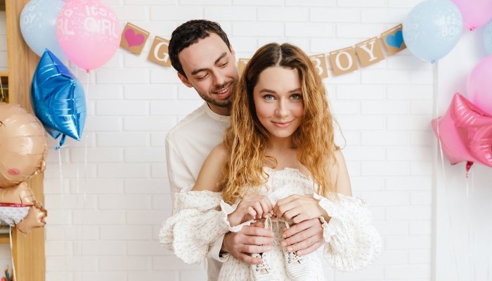 Soon-to-be-parents posing for a picture at their gender-reveal party.