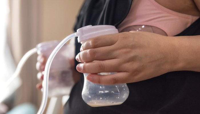 A mother using a breast pump to drain both breasts simultaneously.