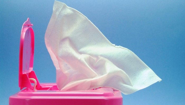 An open box of baby wipes with a pink lid set against a blue background.