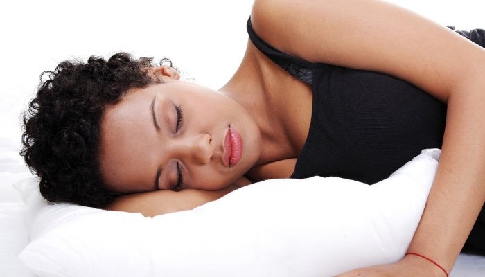 A pregnant woman sleeping with a large pillow to support her breasts.