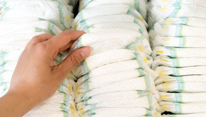 Mother's hand reaches for a diaper from three tall stacks.