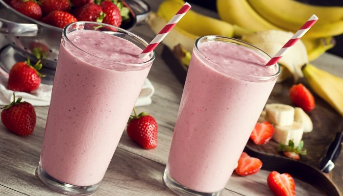 Two strawberry banana smoothies with red-and-white straws.