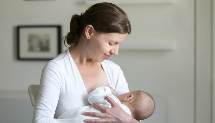 A mother nursing her baby while standing instead of sitting.