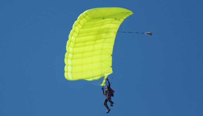 A person sailing through the sky with an open parachute after sky diving.