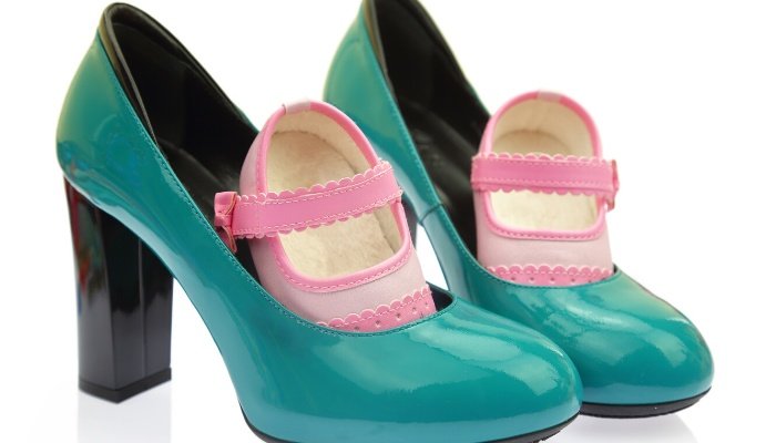 A pair of pink baby shoes nestled inside a pair of blue high heels.