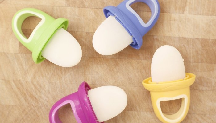 Four breast milk popsicles with colorful handles lying on a wood table.