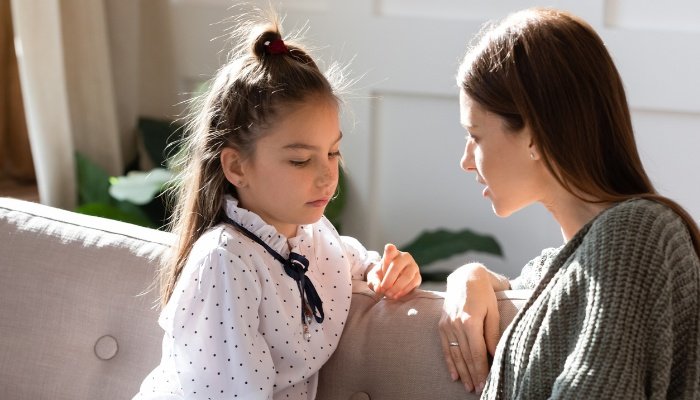 A mother having a serious conversation with her daughter on their couch.