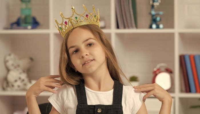 An arrogant young girl with long hair wearing a jeweled crown.