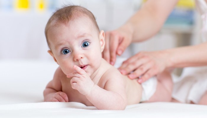 An adorable baby receiving a back massage from his mother.